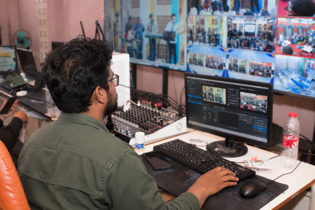 An operator at a control desk, with a wall of monitors showing several camera feeds.
